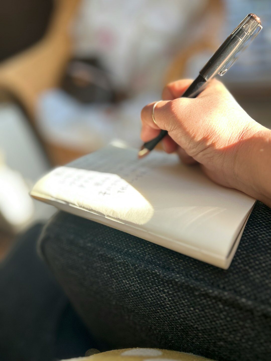 Woman writing notes in a journal at a wooden desk